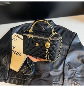 Detail der schwarzen gesteppten Kosmetiktasche mit goldener Kamelie und Metallgriff