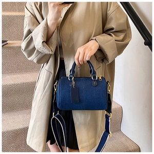 Dettaglio borsa boston in denim blu scuro con manici in pelle e finiture dorate