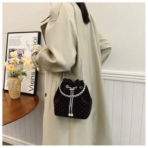 Detail of dark brown velvet bucket bag with white rhinestones and pearl drawstring charm