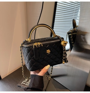 Detailansicht der schwarzen gesteppten Lederbox-Tasche mit goldener Kamelien-Schließe