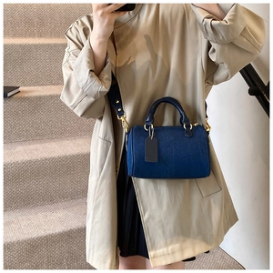 Dettaglio borsa Boston in denim blu navy con manici in pelle e finiture in metallo oro