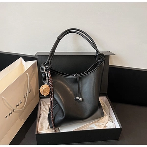 Dettaglio borsa hobo nera con manico a nodo e ciondolo a gatto in confezione regalo di lusso