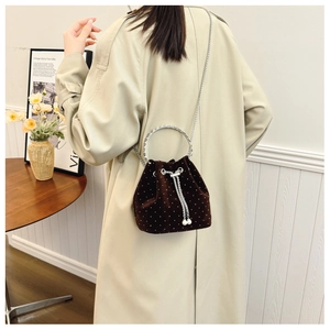 Detail view of brown suede bucket bag with white dots and elegant silver chain strap