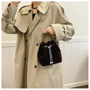Close-up of velvet bucket bag with silver studs, chain strap and pearl drawstring detail