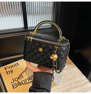 Detailansicht der schwarzen Stepptasche mit goldener Kette und Kamelienblüten-Dekor