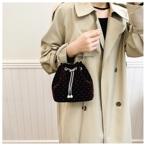 Detail of dark velvet bucket bag with sparkling rhinestones and pearl drawstring