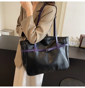 Detail of black tote bag with purple straps and metal buckle on casual suit