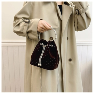 Close-up of brown velvet bucket bag with sparkling rhinestones and metal ring handle