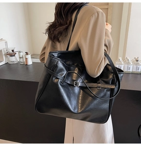 Close-up of high-quality black faux leather tote bag with stylish metal buckle details