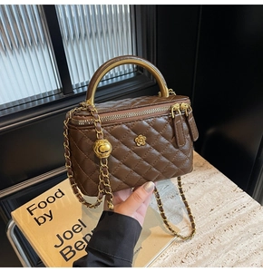 Draufsicht auf eine braune gesteppte Box-Tasche mit Goldkette und Metallgriff auf Marmor