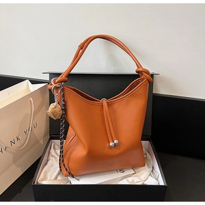 Dettaglio della borsa tote in pelle caramello con ciondolo a gatto in scatola regalo