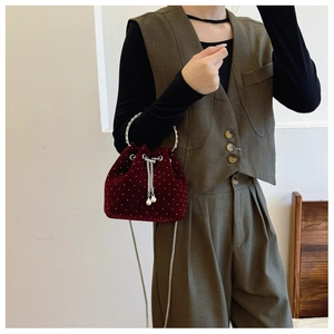 Detailed close-up of burgundy velvet bucket bag with pearl accents and metal handle