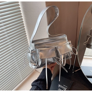 Close-up of silver metallic baguette bag featuring utility pockets and bow knot details