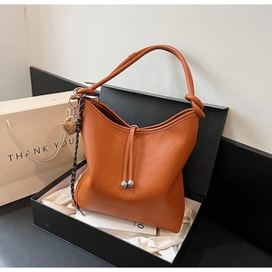 Dettaglio della borsa hobo in pelle caramello con ciondolo fragola in scatola regalo