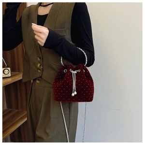 Detail of burgundy velvet bucket bag with white polka dots and pearl chain strap