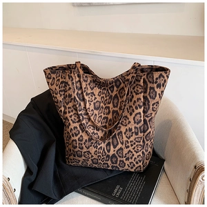 Détail d'un sac cabas léopard posé sur une chaise avec un livre d'art en décoration