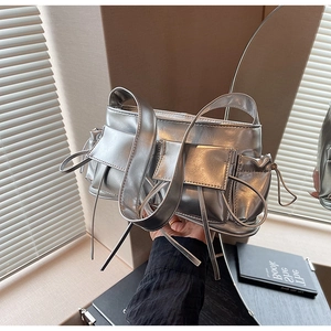 Detailed view of metallic silver baguette bag with utility pockets and bow ribbons