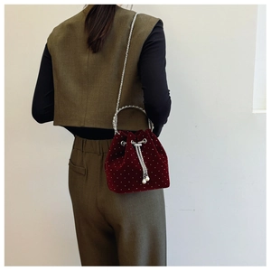 Detail of burgundy velvet bucket bag with silver studs and elegant chain strap