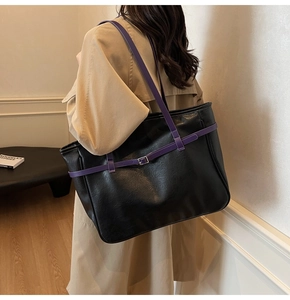Detail of high-capacity black tote bag with purple straps shown on a female model