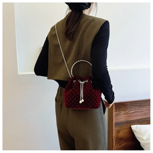 Detail of burgundy velvet bucket bag with white bead accents and silver chain strap