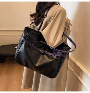 Side view of large black leather tote bag with purple straps on model in trench coat