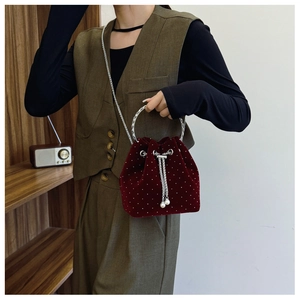Close-up of burgundy velvet bucket bag with rhinestone dots and pearl tassel details