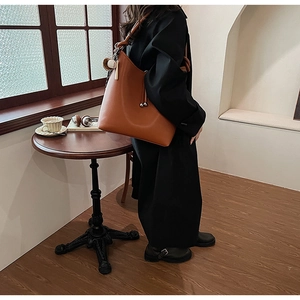 Dettaglio borsa tote in pelle caramello con coulisse laterali e ciondoli a sfera in metallo