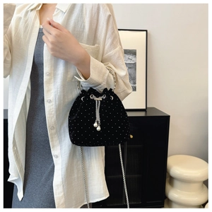 Detail of mini black velvet bucket bag with silver studs, chain strap and pearl drawstring