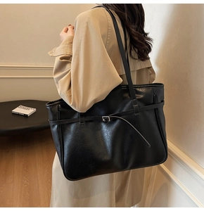 Close-up of black high-capacity leather tote bag with stylish buckle strap details