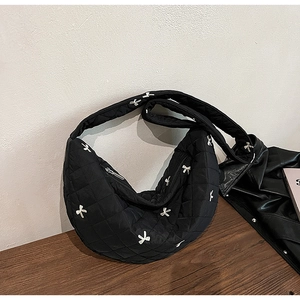 Detail of black quilted crescent bag with white bow embroidery and smooth metal zipper