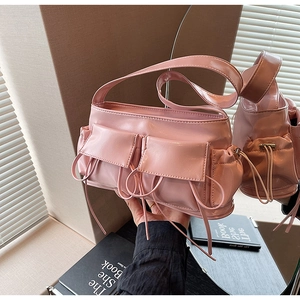 Close-up of pink glossy patent leather shoulder bag with drawstring pockets and bow details