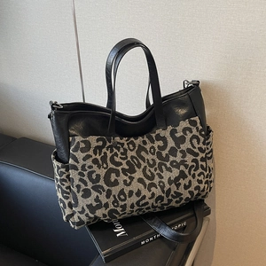 Large black leather tote bag with leopard print pockets and adjustable strap