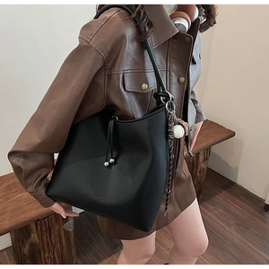 Dettaglio della grande borsa hobo nera in pelle opaca con coulisse e ciondoli sferici