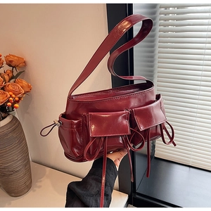 Detail of burgundy glossy faux leather baguette bag with dual pockets and ribbon bows