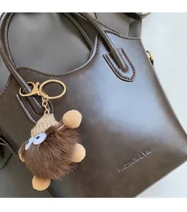 Dettaglio borsa a secchiello in pelle marrone scuro con charm peluche e oro lucido