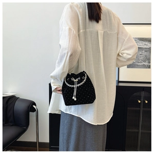 Detail of black velvet drawstring bucket bag with silver dots and pearl chain strap