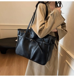 Detail view of large black tote bag with lychee grain texture and buckle strap