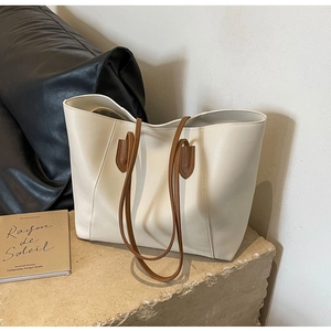 Minimalist beige tote bag on stone base showing the soft PU leather and brown straps