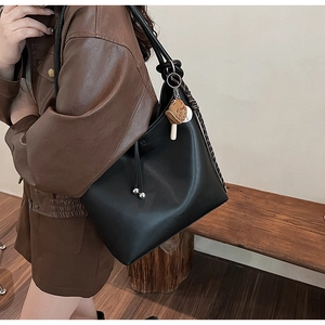Dettaglio della borsa hobo in pelle nera con ciondolo a fungo e logo CLAN inciso