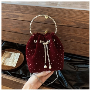 Detail of burgundy velvet bucket bag with pearl embellishments and metal ring handle