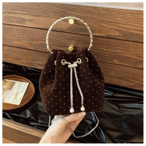 Close-up of brown velvet bucket bag with pearl polka dots and silver ring handle