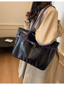 Large black tote bag with purple straps styled with a trench coat for a casual look