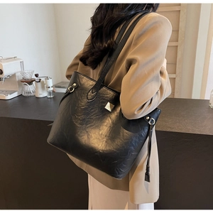 Große schwarze Tote Bag mit Ölwachs-Textur und Quaste an einem weiblichen Model
