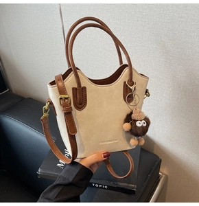 Dettaglio della borsa tote bicolore con bordo ondulato, charm peluche e logo moda