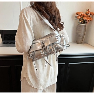Detail of silver metallic baguette bag with decorative bows and ribbons on shoulder