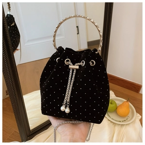 Detail of black velvet bucket bag with silver studs and elegant pearl chain pendant
