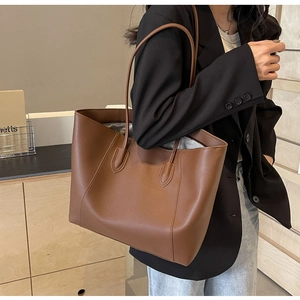 Detail of dark brown tote bag with premium leather texture and long shoulder straps