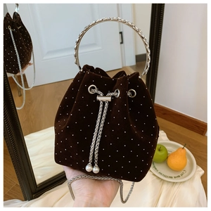 Detail of velvet bucket bag with rhinestones, metal ring handle and pearl drawstrings