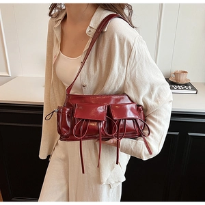 Close-up of a burgundy patent leather underarm bag with decorative drawstring bows