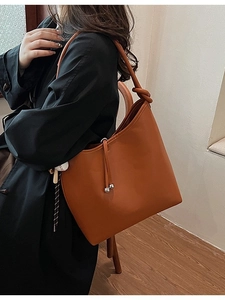 Borsa a secchiello minimalista in pelle color caramello con tracolla a nodo e dettagli